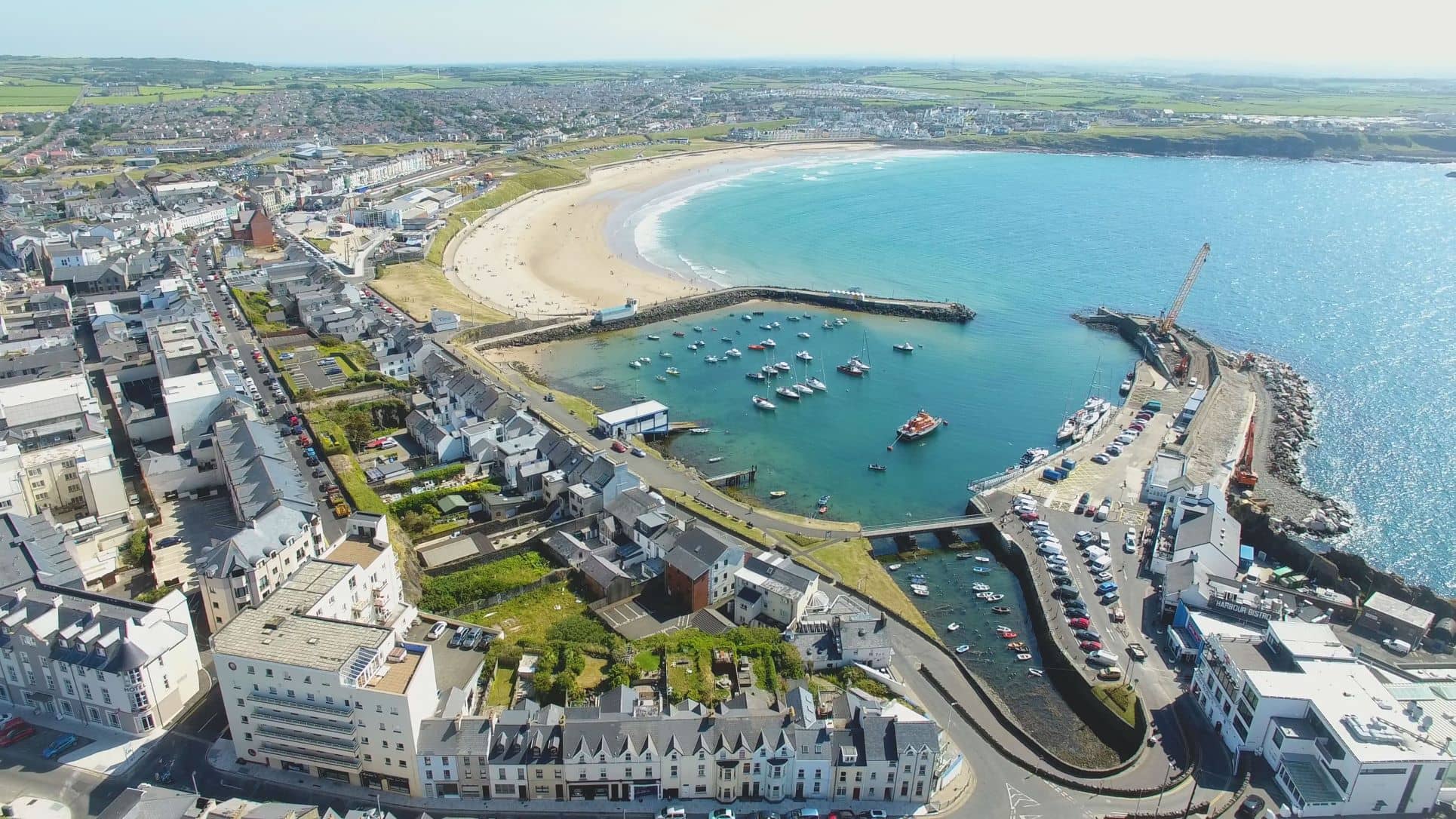 Aerial view of Portrush harbour, West Strand beach, and the town